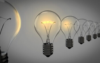 Row of clear glass incandescent light bulbs lit in a line, fading into the distance.